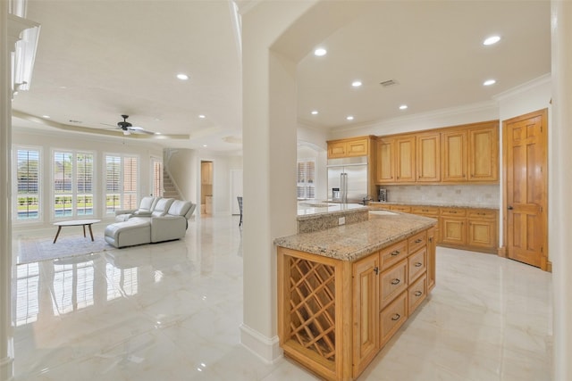 kitchen with crown molding, marble finish floor, built in fridge, and backsplash