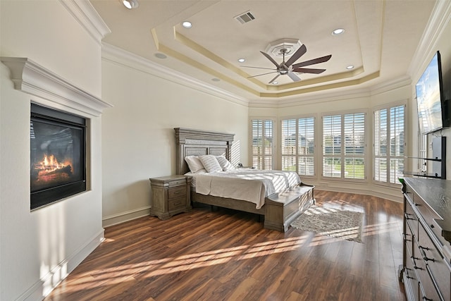 bedroom featuring ornamental molding, dark wood-type flooring, visible vents, a tray ceiling, and baseboards