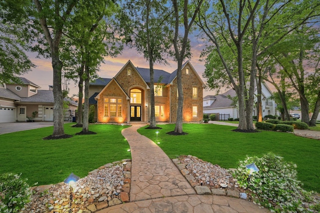 traditional-style house featuring a yard, brick siding, and french doors