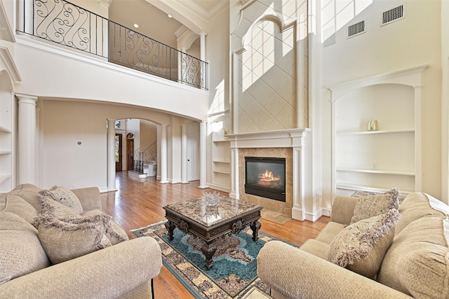 living area featuring built in features, visible vents, a high ceiling, and arched walkways