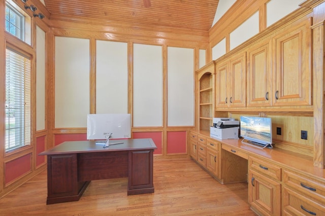 office area with built in desk, light wood-style floors, a decorative wall, and a healthy amount of sunlight