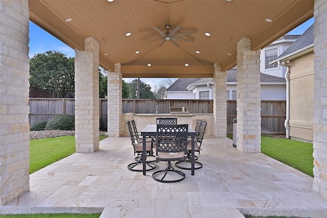 view of patio featuring a fenced backyard, ceiling fan, exterior kitchen, and outdoor dining space