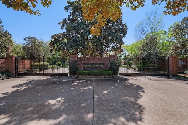 community / neighborhood sign featuring fence and a gate