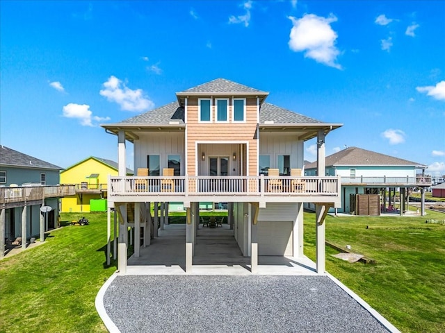back of property featuring roof with shingles, a garage, a carport, and gravel driveway
