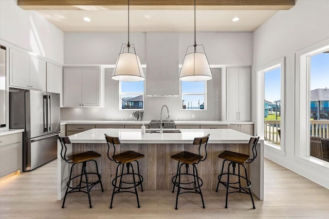 kitchen featuring high quality fridge, a wealth of natural light, decorative backsplash, and a sink
