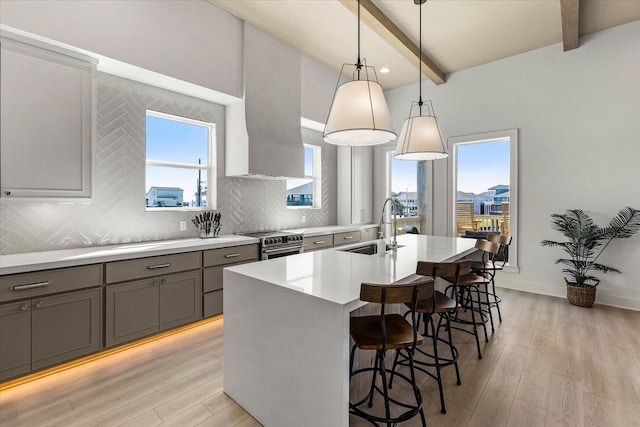 kitchen featuring a sink, gray cabinets, beam ceiling, light wood finished floors, and decorative backsplash