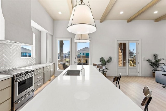 kitchen featuring light wood finished floors, a sink, electric stove, light countertops, and beam ceiling