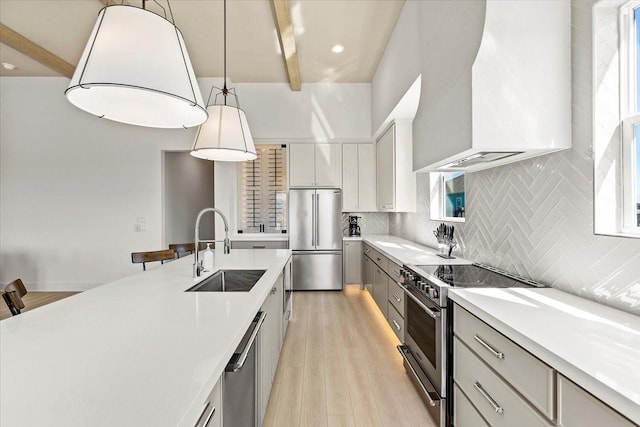 kitchen with light countertops, appliances with stainless steel finishes, a sink, and decorative backsplash