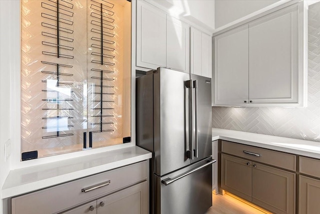 kitchen featuring light countertops, tasteful backsplash, high end refrigerator, and gray cabinetry