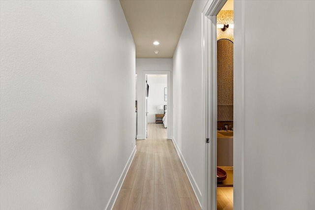 hall featuring light wood-style floors, baseboards, and recessed lighting