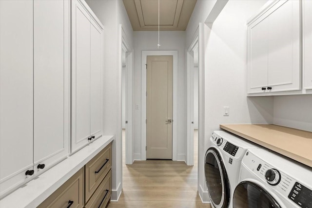 washroom featuring light wood finished floors, cabinet space, attic access, baseboards, and independent washer and dryer