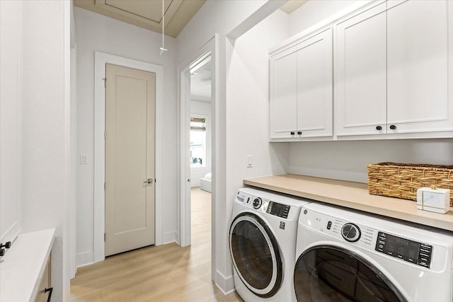 laundry room featuring light wood finished floors, independent washer and dryer, attic access, and cabinet space