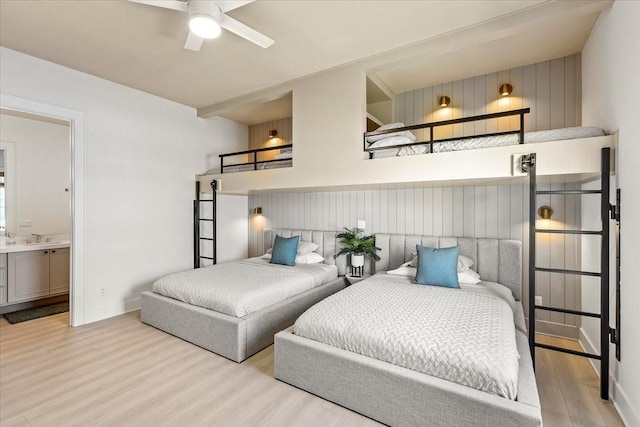 bedroom featuring baseboards, connected bathroom, a sink, and wood finished floors