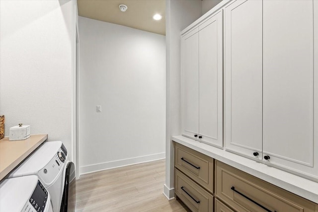washroom featuring light wood-style flooring, recessed lighting, baseboards, washer and clothes dryer, and cabinet space