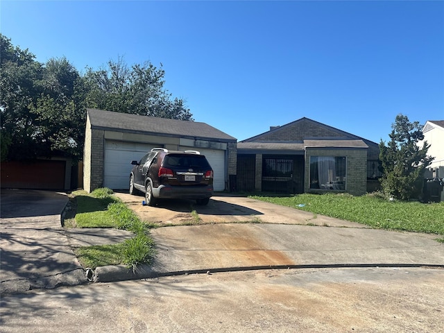 ranch-style home with concrete driveway, brick siding, and an outbuilding