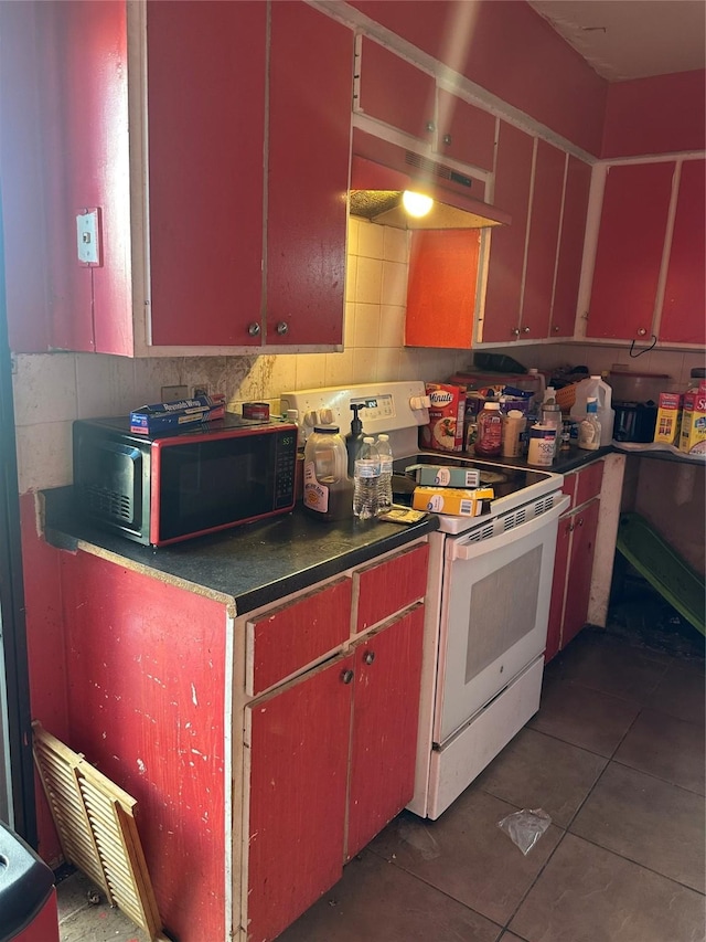 kitchen with dark countertops, tile patterned floors, electric stove, and under cabinet range hood