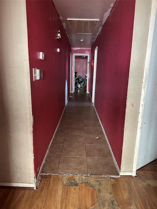 hallway with attic access and baseboards