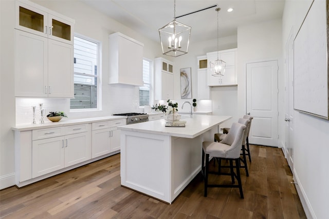 519 W 27th St, Houston, TX 77008 - kitchen with white cabinetry, backsplash, an island with sink, and glass insert cabinets