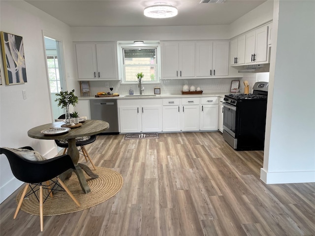 1107 Dover Cir, Alvin, TX 77511 - kitchen featuring appliances with stainless steel finishes, healthy amount of natural light, light wood-type flooring, and white cabinetry