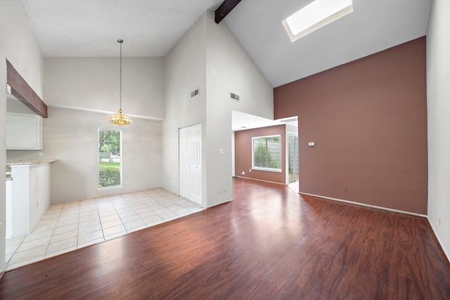 unfurnished living room with light wood finished floors, beamed ceiling, high vaulted ceiling, and visible vents