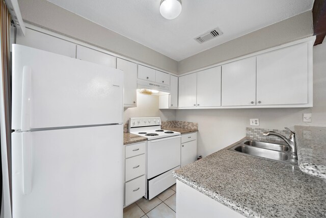 kitchen with a sink, white appliances, visible vents, under cabinet range hood, and white cabinets