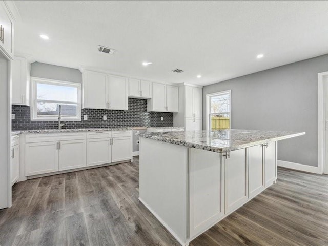 kitchen featuring plenty of natural light, backsplash, visible vents, and white cabinets