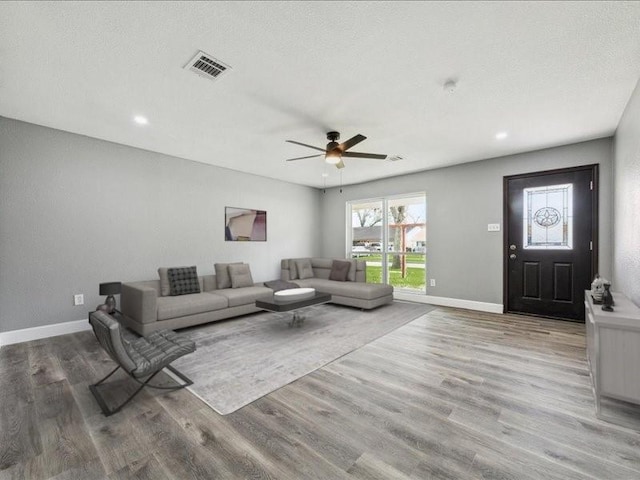 living area featuring a ceiling fan, baseboards, visible vents, and wood finished floors
