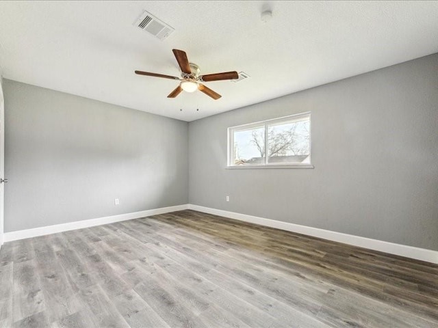 spare room featuring ceiling fan, baseboards, visible vents, and wood finished floors