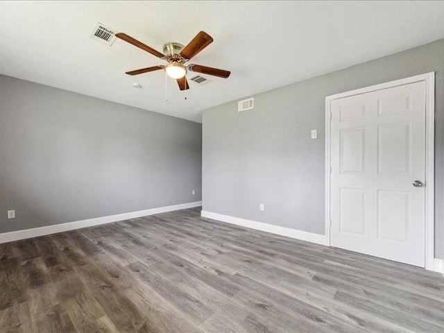 spare room with a ceiling fan, baseboards, visible vents, and wood finished floors