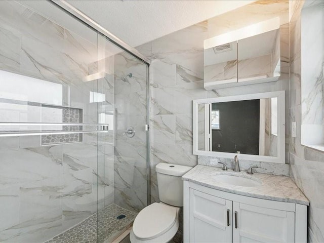 bathroom with a marble finish shower, tile walls, vanity, and toilet