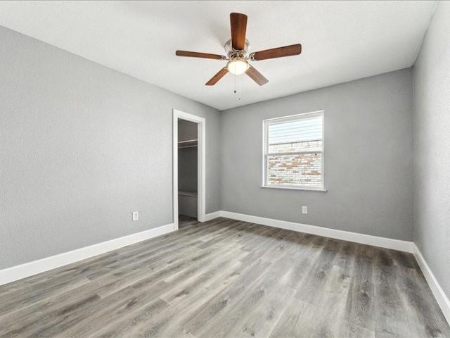 unfurnished bedroom featuring baseboards, a closet, ceiling fan, and wood finished floors