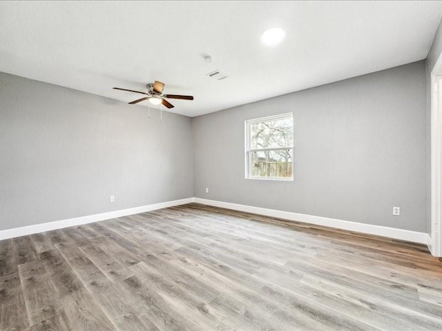 unfurnished room featuring wood finished floors, visible vents, baseboards, and a ceiling fan
