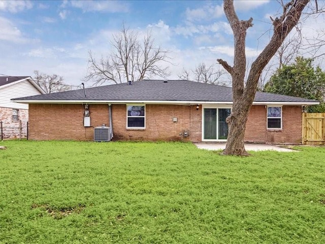 back of property featuring fence, a lawn, central air condition unit, brick siding, and a patio area