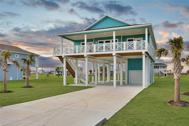 coastal inspired home featuring a carport, driveway, a front yard, and a garage