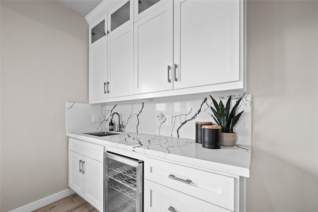 indoor wet bar featuring wine cooler, baseboards, backsplash, and light wood-style flooring
