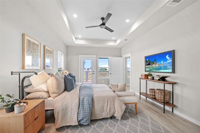 bedroom featuring access to outside, wood finished floors, recessed lighting, baseboards, and a tray ceiling