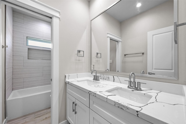 bathroom featuring double vanity, wood finished floors, shower / washtub combination, and recessed lighting