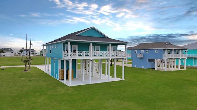 back of property featuring a patio area, a yard, a carport, and roof with shingles