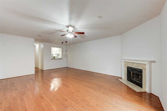 unfurnished living room with a premium fireplace, ceiling fan, light wood-style flooring, and visible vents