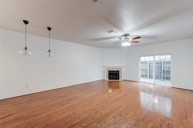 unfurnished living room featuring a ceiling fan, a fireplace with flush hearth, light wood finished floors, and visible vents