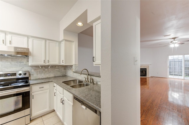kitchen with a sink, under cabinet range hood, a ceiling fan, light stone countertops, and appliances with stainless steel finishes
