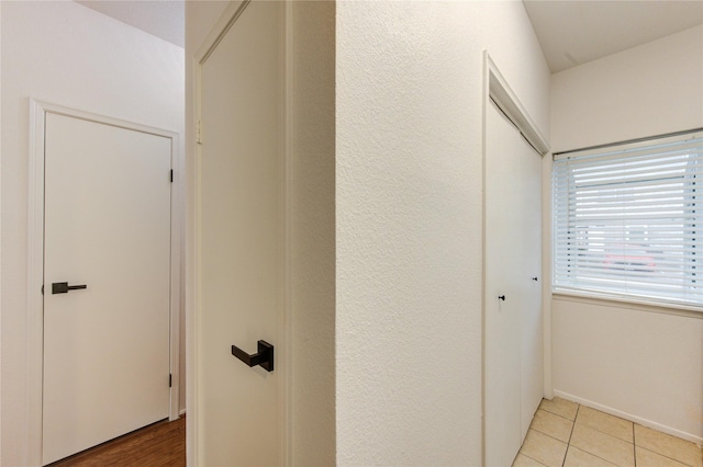 hallway with light tile patterned floors and baseboards