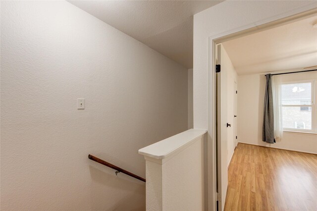 hall with an upstairs landing and light wood-style flooring