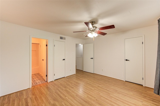 unfurnished bedroom with light wood-style flooring, ensuite bathroom, a ceiling fan, and visible vents