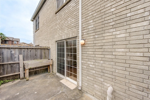 view of home's exterior with brick siding, fence, and a patio
