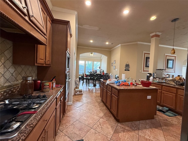 kitchen with stainless steel appliances, arched walkways, decorative backsplash, a kitchen island, and recessed lighting