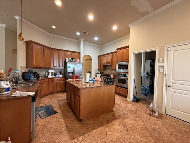 kitchen with dark stone countertops, a sink, crown molding, backsplash, and appliances with stainless steel finishes