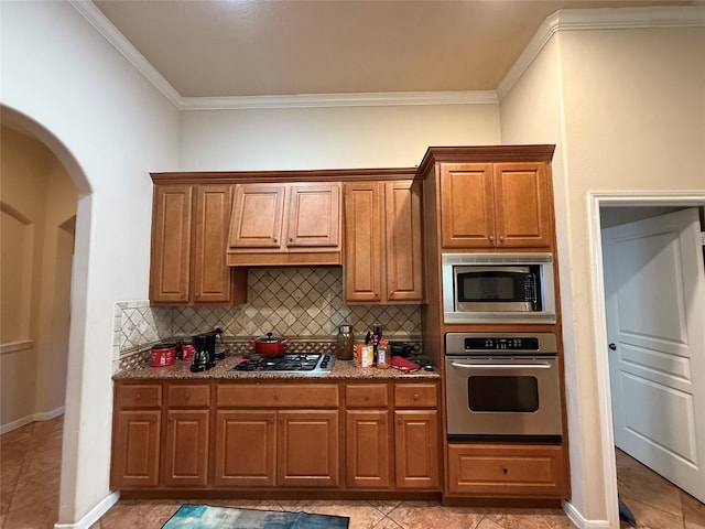 kitchen featuring stainless steel appliances, brown cabinets, ornamental molding, and backsplash