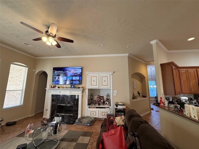 living room featuring a premium fireplace, a ceiling fan, visible vents, tile patterned flooring, and arched walkways