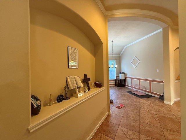 corridor featuring baseboards, a chandelier, crown molding, vaulted ceiling, and arched walkways